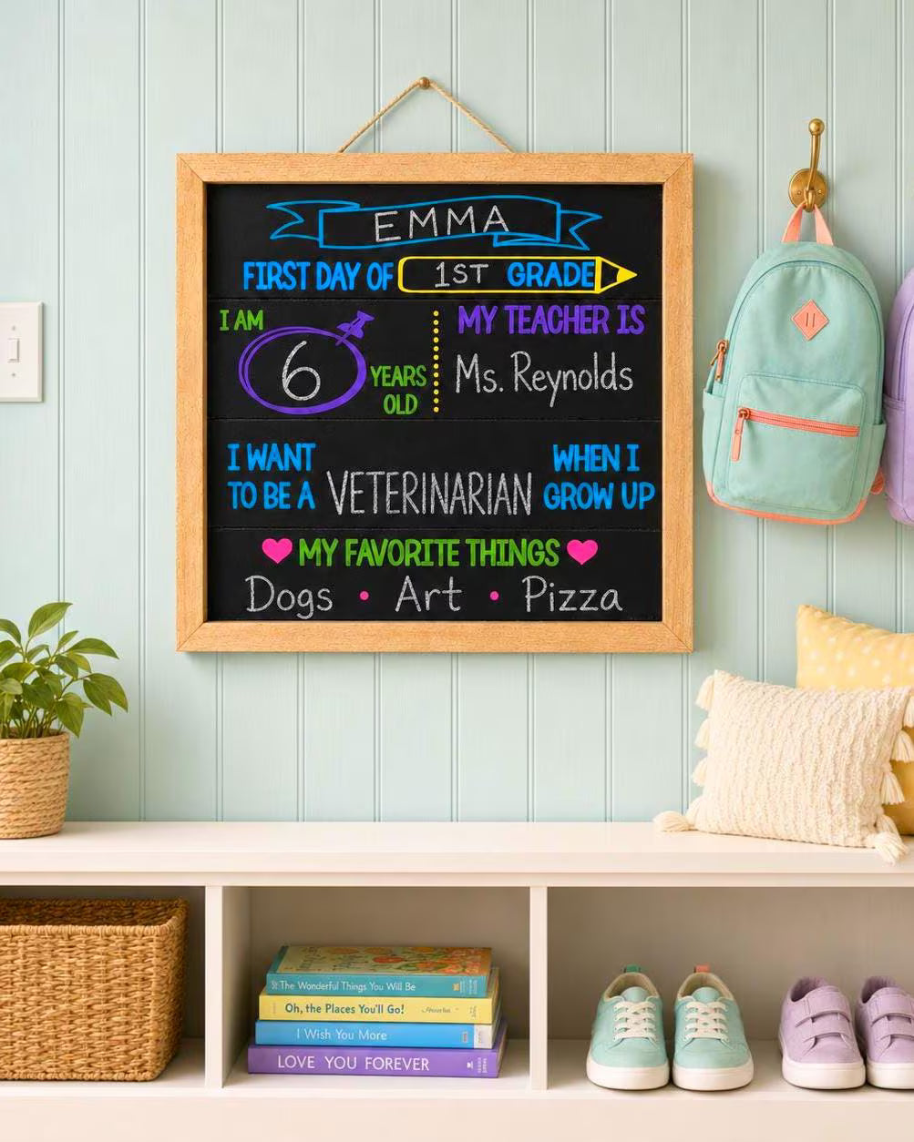 Completed first-grade Favorite Things chalkboard sign hanging in a bright aqua entryway with pastel backpacks, books and children’s shoes.