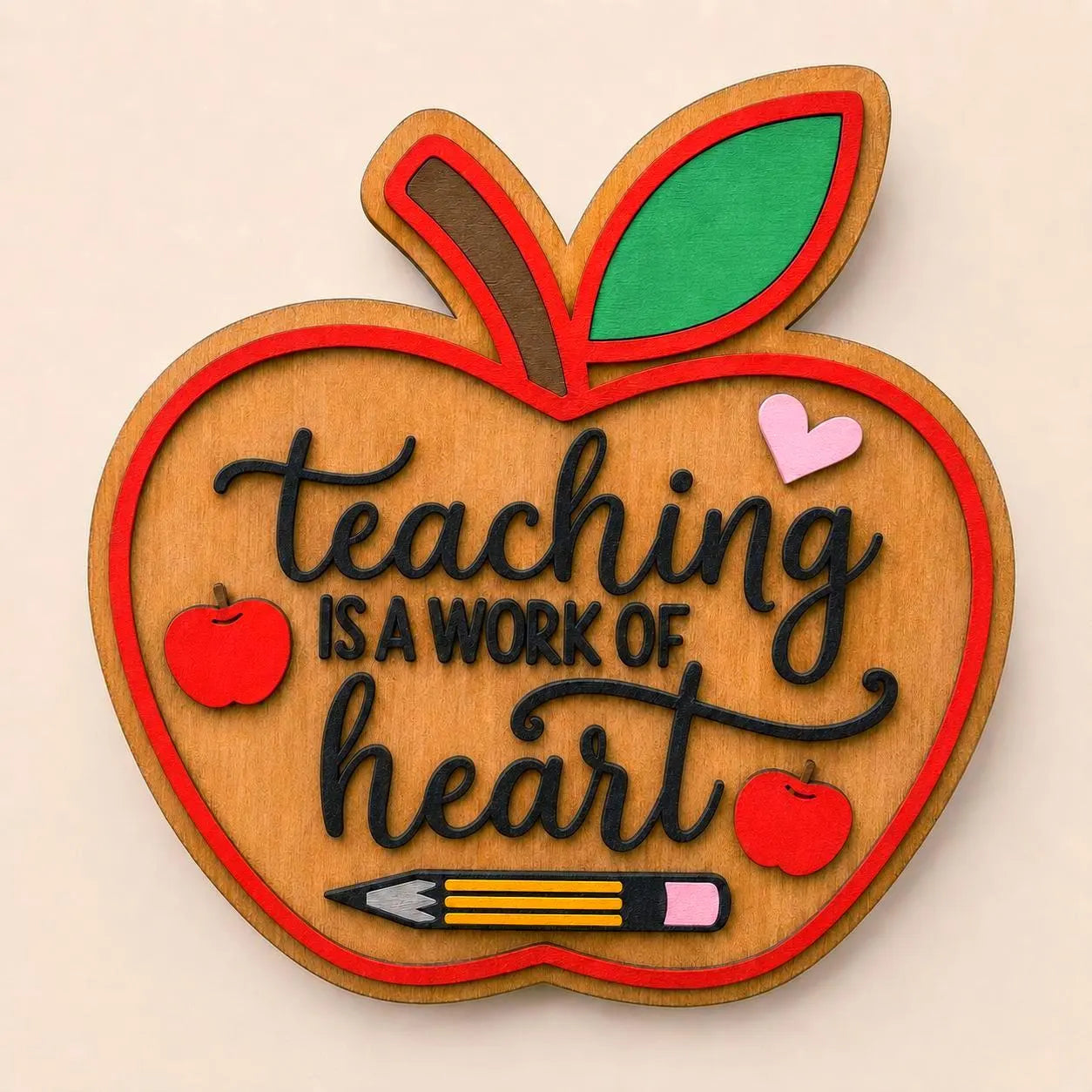 Layered wooden apple teacher sign reading “Teaching Is a Work of Heart” with colorful apples, heart, leaf, and pencil details.