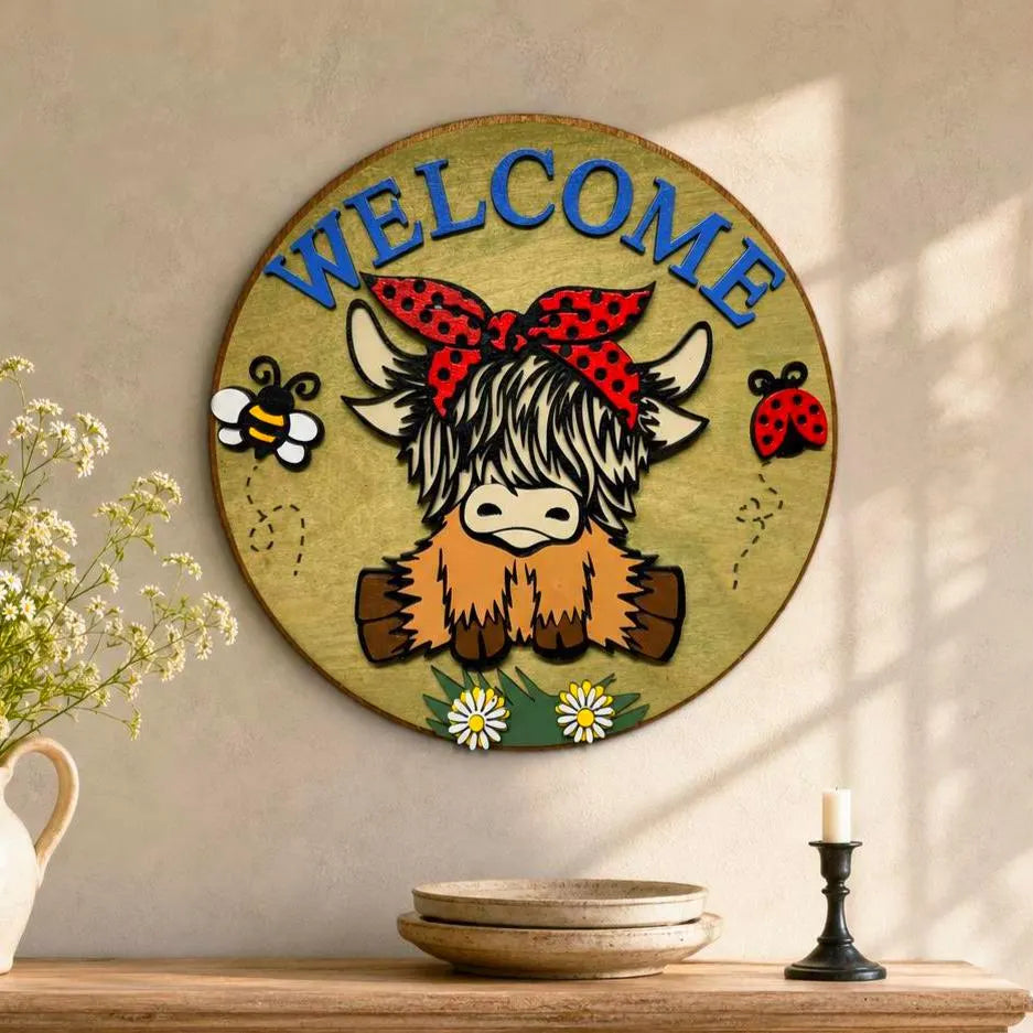 Layered shaggy Highland cow Welcome sign above an oak dining-room sideboard styled with wildflowers, pottery and a candlestick.